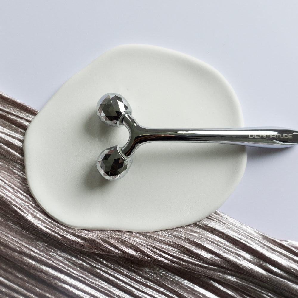 A metal face roller on a white plate.