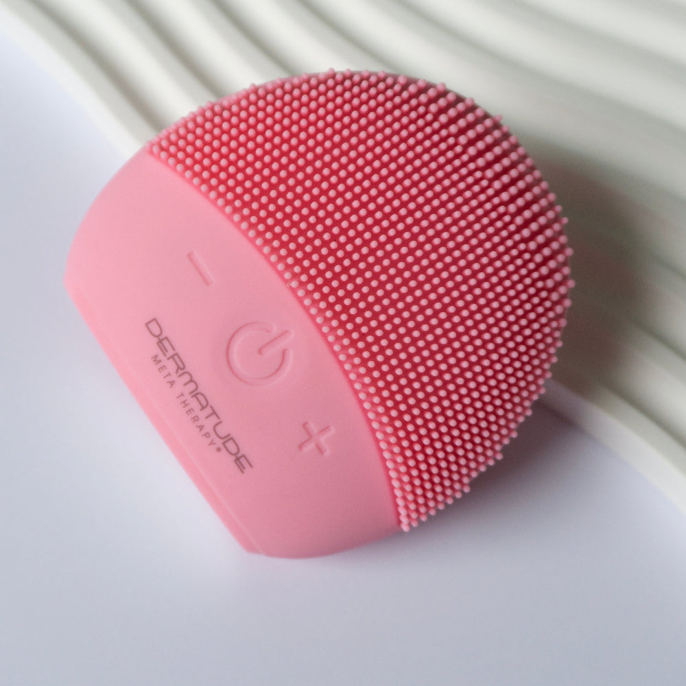 Pink electronic face cleaner. Gentle facia cleanser brush on a white decorative background.