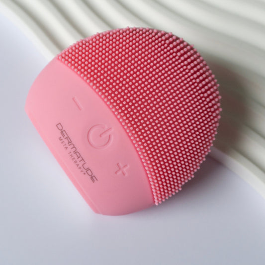Pink electronic face cleaner. Gentle facia cleanser brush on a white decorative background.